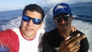 Two Witchs Rock Surf Camp employees on a boat, ocean backdrop.
